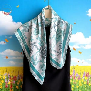 May include: A white silk scarf with a green border and a floral pattern. The scarf has the word "EDEN..." printed on it.