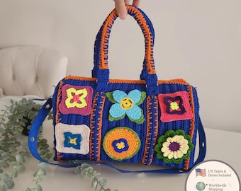 May include: A rectangular crochet handbag in royal blue with orange trim and handles. The bag features various colorful floral and geometric motifs in shades of pink, yellow, light blue, green, and cream, with a detachable blue shoulder strap.