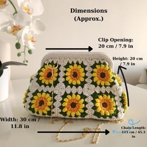 May include: Crocheted clutch with sunflower design. The bag is cream-colored with yellow and green sunflower motifs. Dimensions are approximately 11.8 inches wide, 7.9 inches high, and a chain length of 45.3 inches. The clip opening is 7.9 inches.