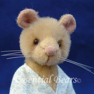 May include: A close-up of a beige plush mouse wearing a blue and white patterned robe. The mouse has pink ears and a pink nose. The mouse has white whiskers.