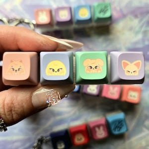 May include: A selection of colourful keyboard keycaps with cartoon animal designs. The square keycaps are in pastel shades like pink, blue, and green. Each keycap displays a different animal illustration.