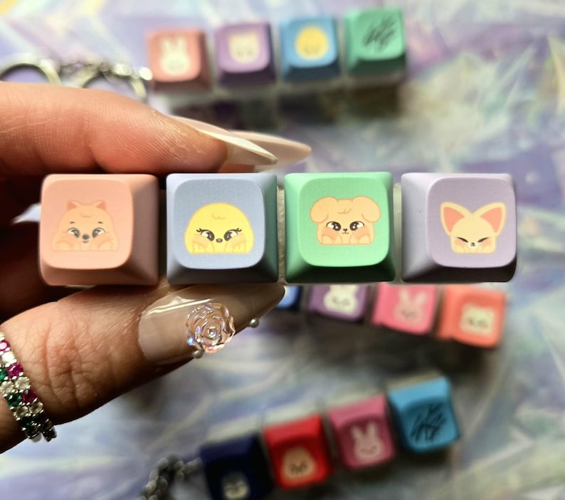 May include: A selection of colourful keyboard keycaps with cartoon animal designs. The square keycaps are in pastel shades like pink, blue, and green. Each keycap displays a different animal illustration.