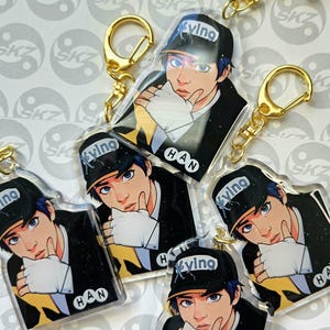 May include: A collection of clear acrylic keychains featuring a stylized illustration of a person wearing a black cap with the word "ying" and the name "HAN". Each keychain has a gold-colored clasp.
