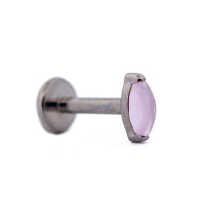 May include: A single, silver-colored lip piercing stud with a light pink, oval-shaped gemstone. The stud has a flat back and a straight post. The gemstone is set in a silver bezel.