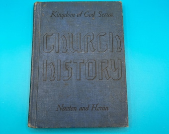 Pode incluir: Um livro azul vintage intitulado "Church History" da "Kingdom of God Series". A capa apresenta letras em relevo e os nomes dos autores, Newton e Horan. O livro está sobre um fundo azul brilhante.