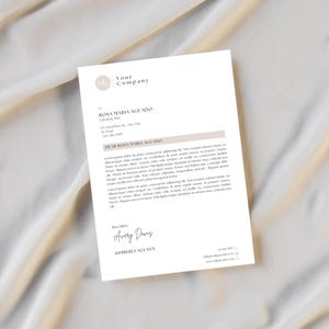 以下が含まれることがあります： 「Your Company」のテキストが上部にあり、Rosa Maria Aguado宛ての白いレターヘッド。手紙には署名と連絡先情報が下部に含まれています。手紙はベージュ色の背景にあります。