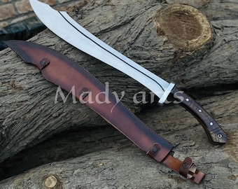May include: A large, curved blade sword with a silver finish and a dark wooden handle. The sword rests on a wooden log with a brown leather sheath. The text "Mady arts" is visible on the sheath.