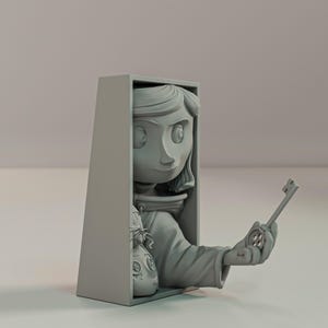 May include: A grey figurine of a girl holding a key and a button. The girl's head and arm extend from a grey rectangular box. A doll-like face is visible in the box. The key is held in the girl's hand.