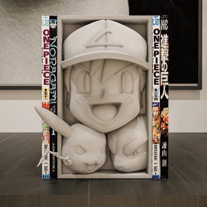 May include: A gray sculpture of a cartoon character with a hat and a smiling face, along with a Pikachu figure. The sculpture is framed by manga books with Japanese text and colorful covers. The sculpture is on a dark surface.