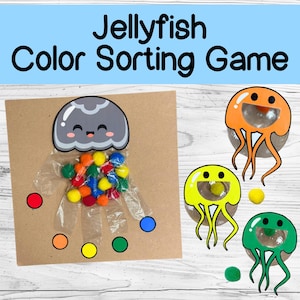 Könnte beinhalten: Ein Medusen-Farbsortier-Spiel für Kinder. Das Spiel enthält eine graue Qualle mit einem durchsichtigen Plastikbeutel, der mit bunten Pompons gefüllt ist. Es gibt vier Quallen in verschiedenen Farben: orange, gelb, grün und blau. Jede Qualle hat ein durchsichtiges Plastikfenster, in das die Pompons fallen können.