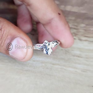 Könnte beinhalten: Ein silberner Ring mit einem Eulen-Design. Die Eule hat weiße und schwarze Markierungen, mit ausgebreiteten Flügeln. Der Ring wird vor einem neutralen Hintergrund präsentiert, der die filigranen Details des Schmucks hervorhebt.