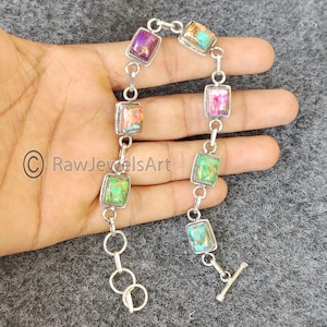 May include: A silver bracelet with a chain link design and square-shaped turquoise, pink, and green stones.