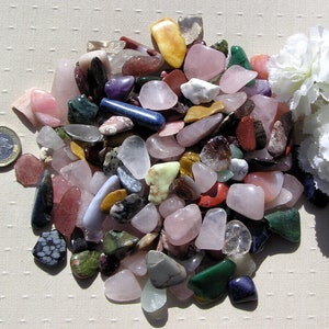 Puede incluir: Una colecci&oacute;n de piedras pulidas de varios colores y formas, incluyendo rosa, verde, azul, rojo y marr&oacute;n. Las piedras est&aacute;n dispuestas en una pila sobre una superficie blanca.