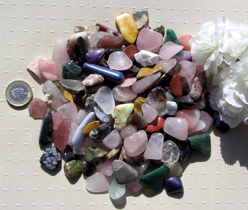 Puede incluir: Una colecci&oacute;n de piedras pulidas de varios colores y formas, incluyendo rosa, verde, azul, rojo y marr&oacute;n. Las piedras est&aacute;n dispuestas en una pila sobre una superficie blanca.