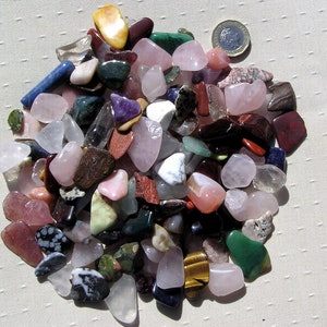 Puede incluir: Una colecci&oacute;n de piedras pulidas de varios colores y formas, incluyendo rosa, verde, marr&oacute;n y azul. Las piedras est&aacute;n dispuestas en una pila sobre un fondo de tela blanca.