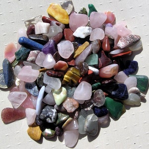 Puede incluir: Una colecci&oacute;n de piedras pulidas de varios colores y formas, incluyendo rosa, verde, azul, marr&oacute;n y amarillo. Las piedras son lisas y pulidas, y est&aacute;n dispuestas en una pila sobre una superficie blanca.