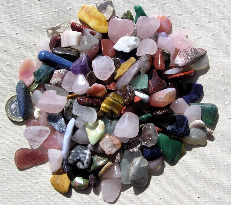Puede incluir: Una colecci&oacute;n de piedras pulidas de varios colores y formas, incluyendo rosa, verde, azul, marr&oacute;n y amarillo. Las piedras son lisas y pulidas, y est&aacute;n dispuestas en una pila sobre una superficie blanca.