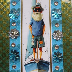 Op de afbeelding: Een rechthoekige wenskaart met een centrale illustratie van een bebaard figuur met een hoed en zonnebril op een zeilboot. De kaart is omrand met blauwe geschulpte patronen, gouden geometrische stroken en metalen bloemvormige versieringen.