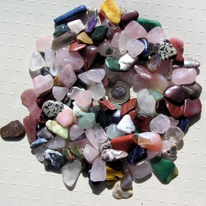 Puede incluir: Una colecci&oacute;n de piedras pulidas de varios colores y formas, incluyendo rosa, rojo, verde, azul y marr&oacute;n. Las piedras est&aacute;n dispuestas en una pila sobre una superficie blanca.