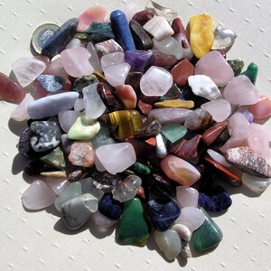 Puede incluir: Una colecci&oacute;n de piedras pulidas de varios colores y formas, incluyendo rosa, verde, rojo, azul y marr&oacute;n. Las piedras est&aacute;n dispuestas en un patr&oacute;n circular sobre una superficie blanca.
