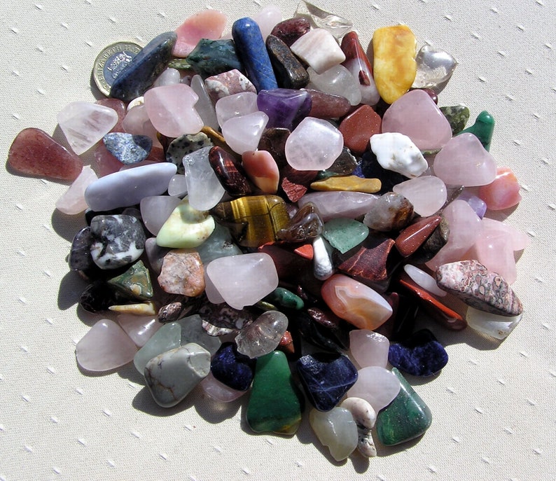 Puede incluir: Una colecci&oacute;n de piedras pulidas de varios colores y formas, incluyendo rosa, verde, rojo, azul y marr&oacute;n. Las piedras est&aacute;n dispuestas en un patr&oacute;n circular sobre una superficie blanca.