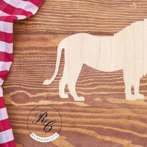 May include: A wooden cutout of a lion's silhouette on a brown wood background. The lion is facing the right side of the image.