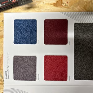 Puede incluir: Un muestrario de telas de tapicer&iacute;a en varios colores y texturas. Las muestras est&aacute;n etiquetadas con los nombres "Ocean", "Ruby", "Fondant", "Cherry" y "Harlem Faux Leather Upholstery Fabric".