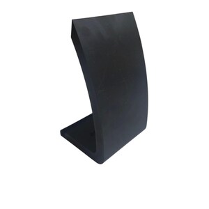 Op de afbeelding: Een zwarte, gebogen displaystandaard met een rechthoekige basis. De standaard heeft een gladde, matte afwerking en een modern, minimalistisch design. De standaard is ontworpen om een item vast te houden.