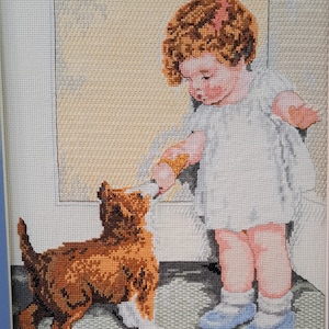 May include: A little girl with curly brown hair and a white dress is feeding a brown and white puppy. The puppy is standing on its hind legs and looking up at the girl.