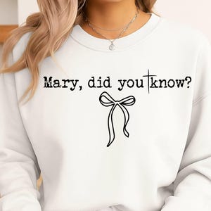 May include: White sweatshirt with the text "Mary, did you know?" in a black, distressed font. A black bow graphic is centered below the text. The sweatshirt is a casual, comfortable style.