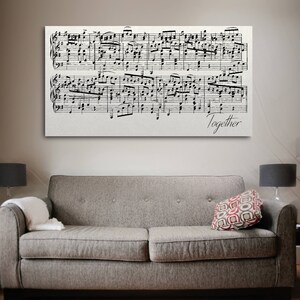 May include: A black and white sheet music print with the word "Together" at the bottom. The print is framed and hanging on a wall above a gray couch.