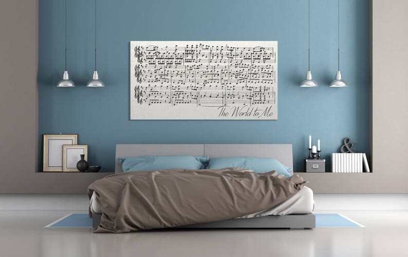 May include: A bedroom with a light blue wall and a bed with a brown comforter and blue pillows. A framed piece of sheet music with the words "The World to Me" hangs above the bed.