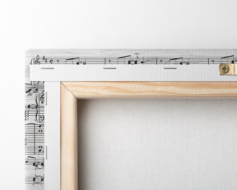 May include: A canvas art print featuring musical notes and a wooden frame. The print has a white background with black musical notation. The wooden frame is light brown. A metal screw is visible on the side.
