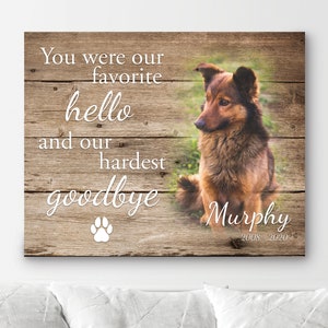 Op de afbeelding: Een houten bord met de tekst "You were our favorite hello and our hardest goodbye" en een pootafdruk. Een bruin-zwarte hond is rechts afgebeeld, met de naam "Murphy" en de jaren "2008-2020" eronder.
