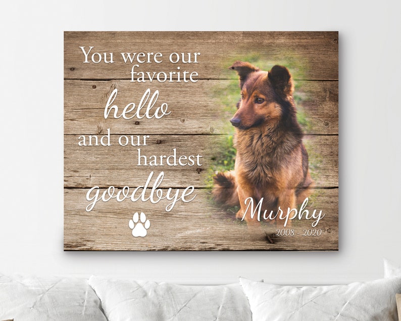 Op de afbeelding: Een houten bord met de tekst "You were our favorite hello and our hardest goodbye" en een pootafdruk. Een bruin-zwarte hond is rechts afgebeeld, met de naam "Murphy" en de jaren "2008-2020" eronder.