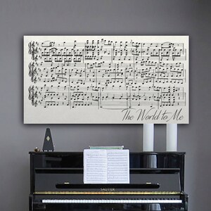 May include: A black and white sheet music print with the words "The World to Me" at the bottom. The music is for a piano and is displayed above a black piano.