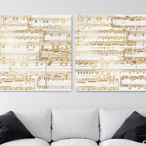 May include: Two white wood panels with gold musical notes printed on them. The panels are hung on a white wall above a white couch.