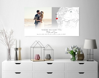 Op de afbeelding: Een ingelijste trouwfoto met een stel, een kaart met een hartmarkering en de tekst "WHERE WE SAID I DO!" met namen en een datum. De print wordt getoond op een witte dressoir.