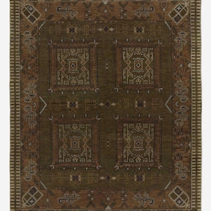 May include: A rectangular, olive green rug with a detailed geometric pattern. The rug features a central square design with four smaller squares, each containing intricate motifs in shades of brown and beige. The border has a repeating pattern.