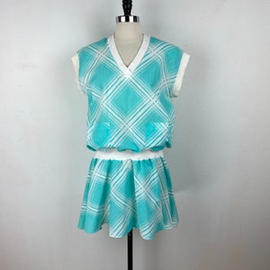 May include: A turquoise and white checked dress with a v-neck and short sleeves. The dress has a fitted bodice and a gathered skirt.