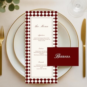 Puede incluir: Una mesa formal con tenedor, cuchillo y platos dorados. Una tarjeta de menú con un borde de patrón de diamantes burdeos y blanco muestra el texto "the Menu" y una lista de platos. Una tarjeta de nombre a juego dice "BARBARA".