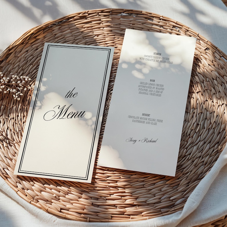 Puede incluir: Dos tarjetas de men&uacute; color marfil con texto negro y borde negro, sobre una bandeja de mimbre tejido. Una tarjeta dice "the Menu" en escritura cursiva. La otra enumera un entrante, un plato principal y un postre, con "Ivory + Richard" abajo.