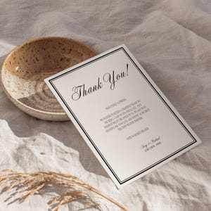Könnte beinhalten: Eine Dankeskarte mit schwarzem Rand und eleganter Schrift, die "Thank You!" lautet. Die Karte enthält eine Nachricht an Familie und Freunde. Eine gesprenkelte Keramikschale steht in der Nähe auf einer neutralen Leinenoberfläche.