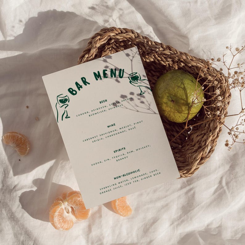 May include: A bar menu with green text and illustrations, listing beer, wine, spirits, and non-alcoholic beverages. The menu is in a woven basket with a lime and orange slices.