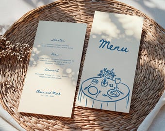 May include: Two cream-colored wedding menu cards with blue text and illustrations. One card says "Menu" with a table illustration. The other lists a starter, main course, and dessert, with names and the date.