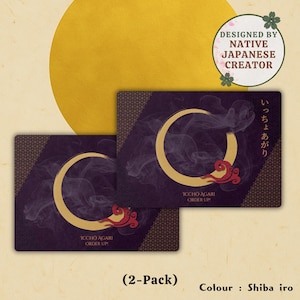 May include: Two rectangular cards with a gold crescent moon design and red accents, set against a dark purple background. The cards feature Japanese text and the words "ICCHO AGARI ORDER UP". The background includes a gold circle and text that reads "DESIGNED BY NATIVE JAPANESE CREATOR".