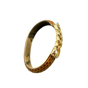 Könnte beinhalten: Ein goldfarbenes Gliederarmband mit einem braunen Lederband.