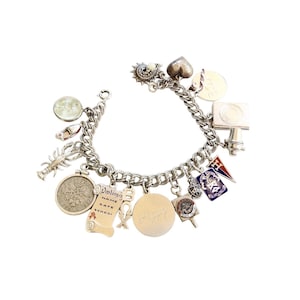 May include: A silver charm bracelet with a variety of charms, including a heart, a sun, a diploma, a lobster, a coin, and a flag. The bracelet is made of a chain link design.