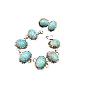 May include: A silver bracelet with turquoise stones and matching earrings. The bracelet has six oval-shaped turquoise stones set in silver.