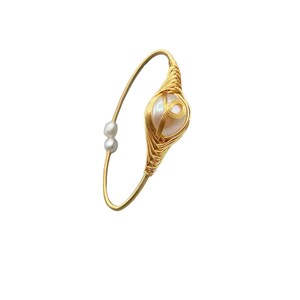 May include: A gold wire wrapped bracelet with a large white pearl in the center. Two smaller white pearls are on the wire near the clasp.